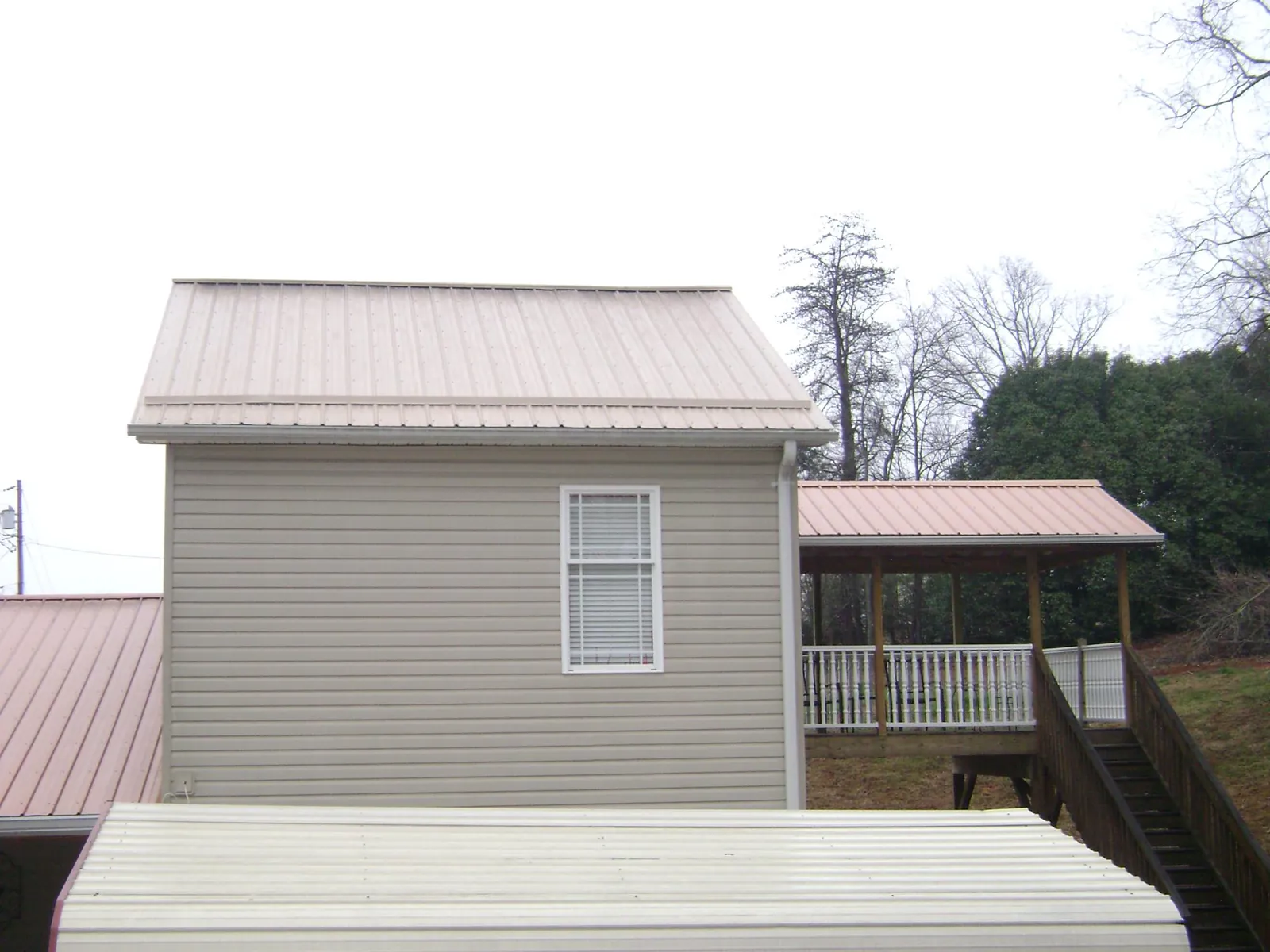 Tan metal roofs on a two story addition and attached porch, from a Roof Replacement job in Boise