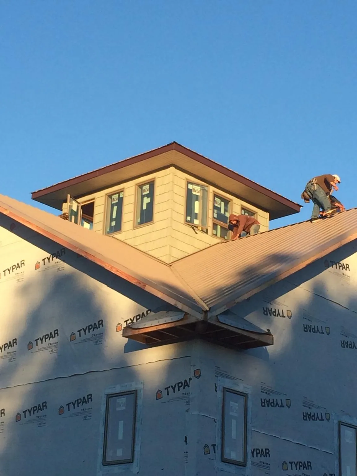 Roofers working around a rooftop cupola on a new metal roof at sunset — Roof Waterproofing in Boise by Roofing Brothers